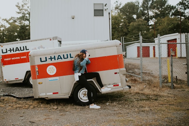 woman sitting next to a uhaul trailer