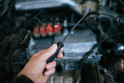 Man with Screwdriver holding it over a car engine 